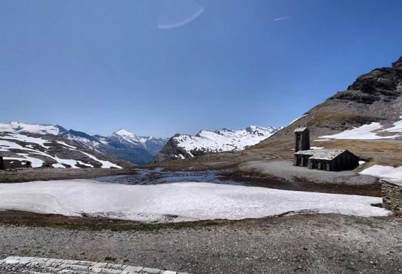  Schneebedeckte Berge, rechts eine Steinkirche. Darüber blauer Himmel. 