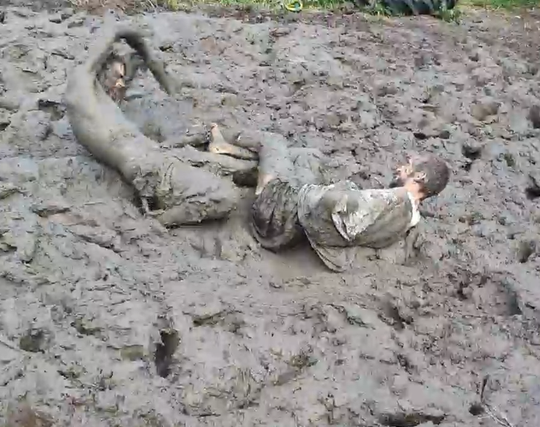 2 mensen liggen in de modder
1 heeft een blote voet (en een arm onder het tshirt)
 de ander steelt de sok