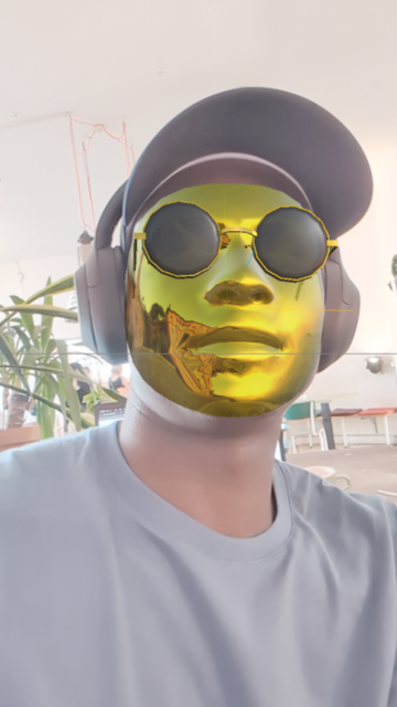 A selfie with an AR filter applied that overlays a gold mask and round sunglasses.