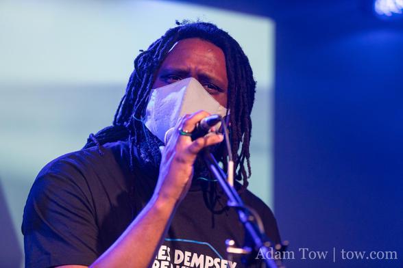 T.J. Usiyan on stage at the microphone wearing a JDBP t-shirt. Photo by Adam Tow.