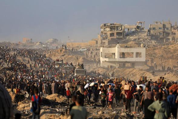 3 trucks of aid (flour) amongst crowds of people with the background of bombed out houses.