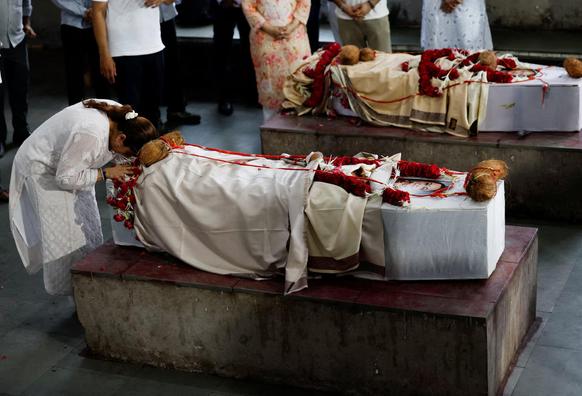 Meena Patel's daughter bows over her mother’s coffin decorated with flowers.