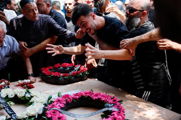 A man mourns as relatives and friends attend a funeral.