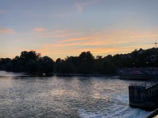 Sunset over some tree, a river in the foreground