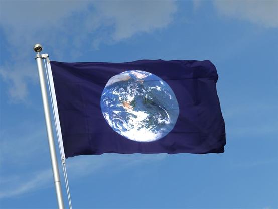 A flag with the image of Earth as seen from Space on dark blue background against light blue sky.