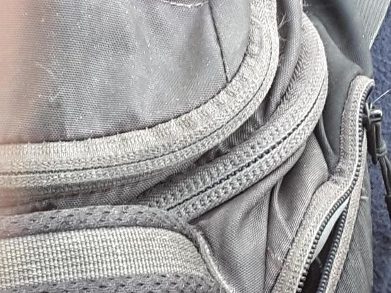 Closeup of the top of a worn grey canvas knapsack, a number of varying monochrome textures, side by side. On the right side an indigo felt shows this is a color photo.