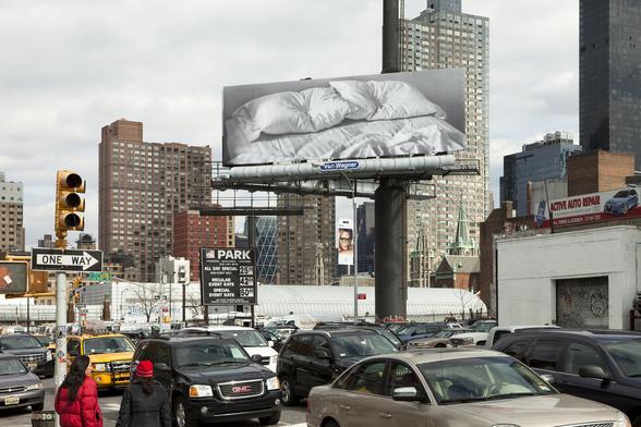 Large scale photo of artist's bed in museum and on billboards.