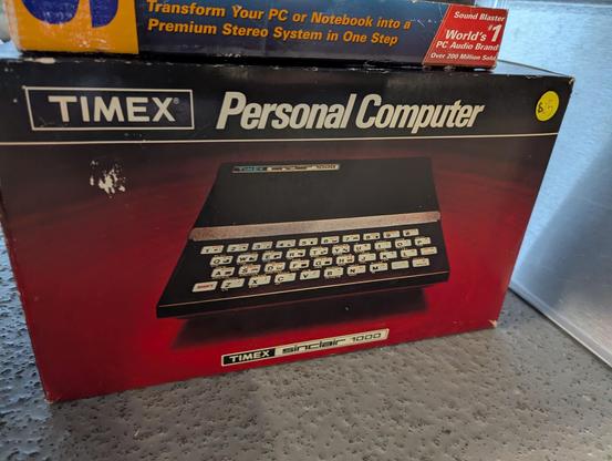 A photograph of a Timex Sinclair 1000 personal computer, for sale in its original box at the MIT Flea in Cambridge, Massachusetts, USA on 2025.06.15.  The price tag is $25.
