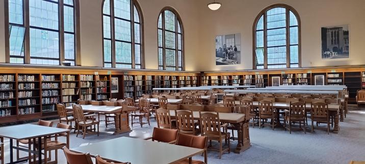 Main study hall at WWU library, showing many seats and tables surrounded by bookshelves and large windows. No AC outlets though :(