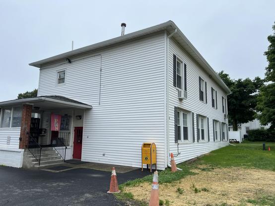 exterior of the Plattekill Library in Modena. It’s a simple, boxy, white structure with a porch at one end for books which are given away. 