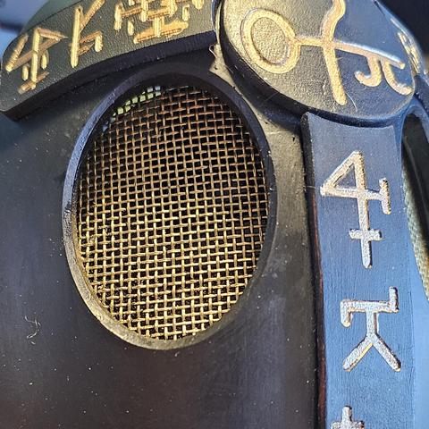 A close up of a 3d printed mask centered on the gold mesh eye hole