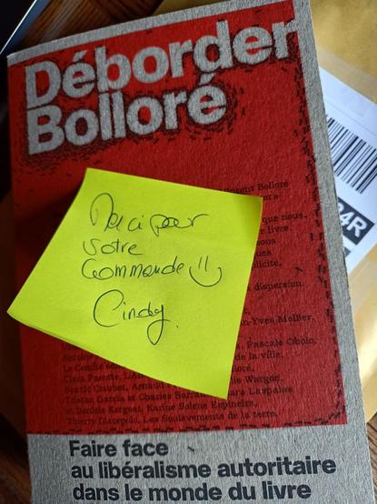 Photo du Livre déborder Bolloré , éditions collective, écriture collective avec un post-it jaune avec écrit à la merci pour votre commande 🙂 cindy