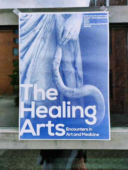 The Healing Arts - Encounters in Art and Medicine poster on a glass door. Kerstins shilouette can be slightly seen in the mirroring window glas.