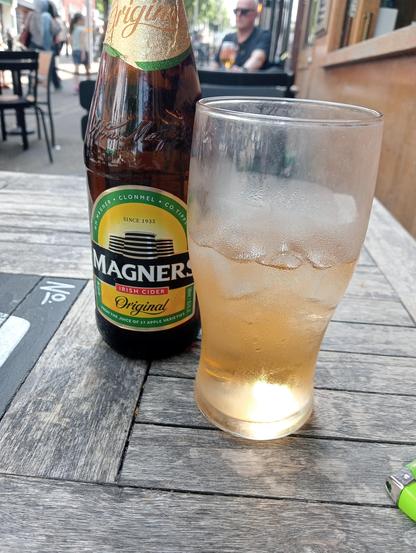 A bottle of cold Irish Cider and a pint glass half full of ice