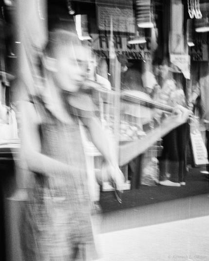 Black and white ICM photo of a fiddler busking at Pike Place Market.