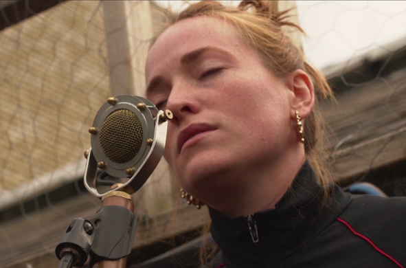 Radie in front of a mic, eyes closed, on a rooftop