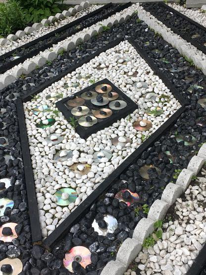 A colourful garden featuring an assortment of stones and reflective CDs scattered throughout the landscape.