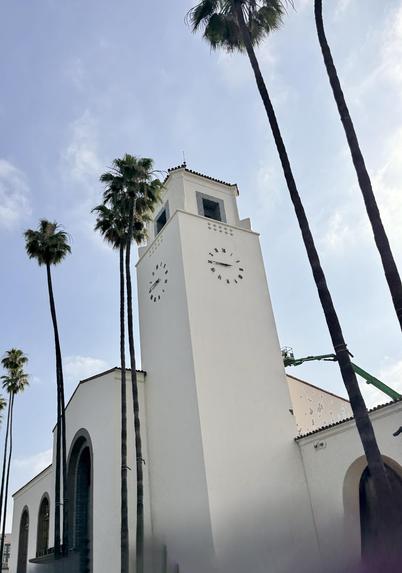 Clock tower in front of Union Station Los Angeles. Palm trees and blue sky.