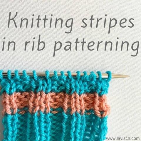 A swatch in salmon pink and turquoise yarn showing stripes on a knitting needle.