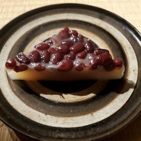 A traditional triangular sweet known as minatsuki or mizazuki. Red beans cover a layer of soft mochi.