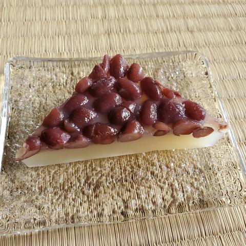 A traditional triangular sweet known as minatsuki or mizazuki. Red beans cover a layer of soft mochi.