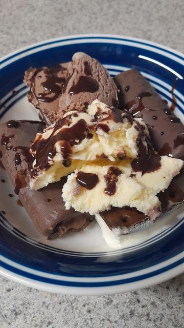 Picture of a bowl with ice cream, chocolate syrup and Swiss rolls with ice cream Sandwich at the bottom
