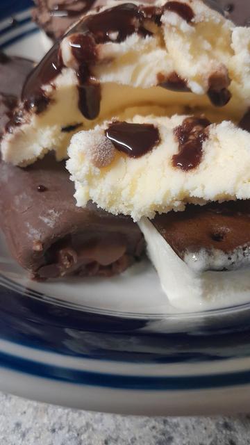 Picture of a bowl with ice cream, chocolate syrup and Swiss rolls with ice cream Sandwich at the bottom