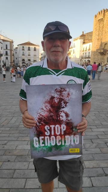 Un hombre, en la Plaza Mayor de Cáceres, sosteniendo un cartel con el lema STOP GENOCIDIO.