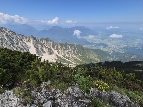A stunning mountain landscape is depicted in this image, showcasing a mountain with lush green trees in the foreground and majestic mountains in the background. The sky is a beautiful shade of blue with fluffy white clouds scattered across it. This serene outdoor scene exudes a sense of tranquility and natural beauty, perfect for anyone looking to escape into the wilderness. The image captures the essence of nature, highlighting the rugged terrain and vast expanse of the mountain range.