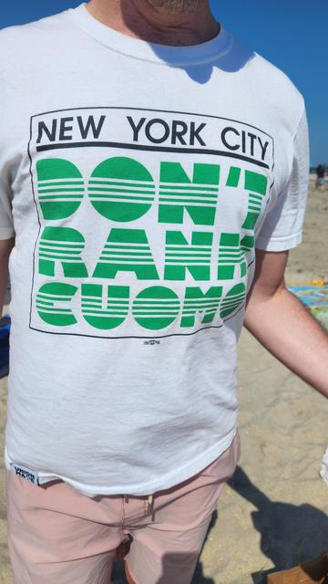 Torso of a person wearing a political parody t-shirt that mimics the well-known logo of the NYC Department of Transportation, but instead says:  NEW YORK CITY DON'T RANK CUOMO.