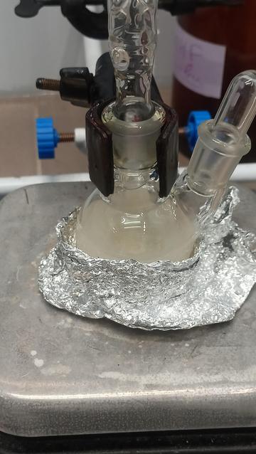 round bottom flask on a hotplate with a suspension of grey product in it