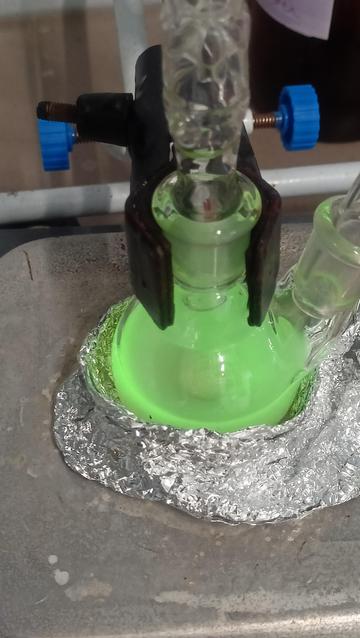 same flask under uv exhibiting fluorescence emitting green light