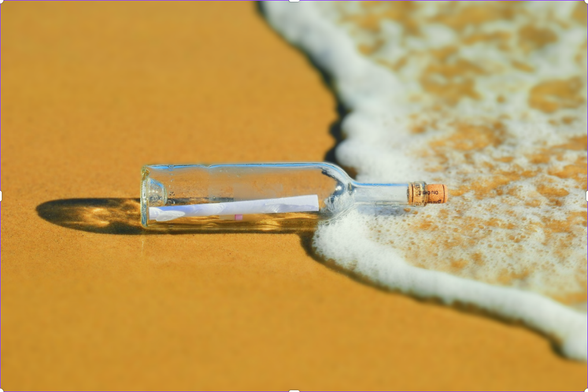 Immagine di una bottiglia di vetro con tappo in sughero e un foglietto dentro come messaggio su una spiaggia, il classico messaggio in bottiglia.