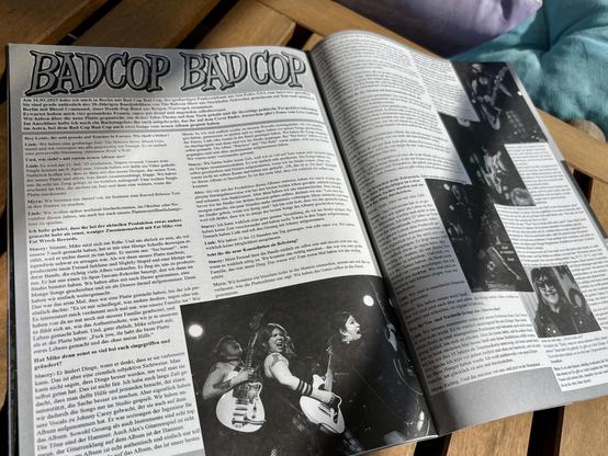 The image shows an open magazine article featuring an interview with the band Bad Cop / Bad Cop. The text is in German and discusses their upcoming album and tour, alongside black-and-white photos of the band performing. The magazine is placed on a wooden surface.