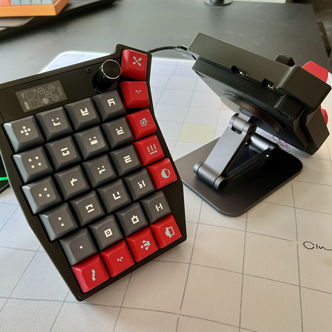 2/2 of a dark split economic keyboard tented, using a folded iPhone stand