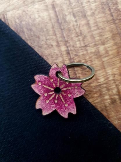 Leather pink sakura (cherry blossom) keychain on a black and wood background