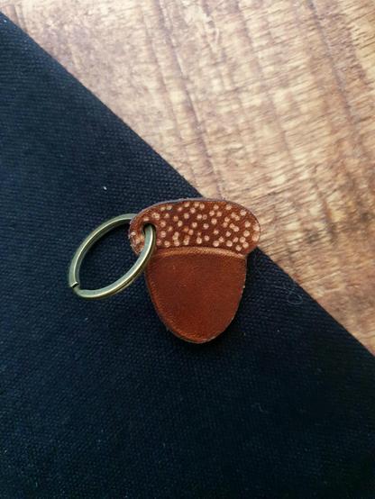 Leather brown acorn keychain on a black and wood background