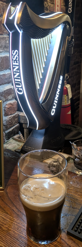Harp-shaped Guinness draught dispenser, with (my) half-pint of Guinness in front of it.