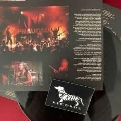 Ein Arrangement einer Vinyl-Schallplatte zusammen mit dem Albumcover und einer Werbekarte. Das Albumcover zeigt eine Live-Konzertszene mit bunten Lichtern und einer auftretenden Band.