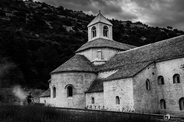 Délicatement posée dans son vallon provençal, l’abbaye de Sénanque, du haut de son petit clocher de lauzes, affronte bravement depuis près de 900 ans les assauts d’un mistral peu aimable.

Fondée au XIIème siècle par un ordre monastique porté par l’aura de Saint Bernard, elle offre une architecture romane aux lignes douces et pures, aux proportions humaines. Sobre et dépouillée, où l’invisible devient visible, où rien ne détourne le moine de sa prière.

« Sénanque, longtemps oubliée dans sa solitude, conservée par miracle, est une relique du Moyen-Age. » M. Montrond (1858)