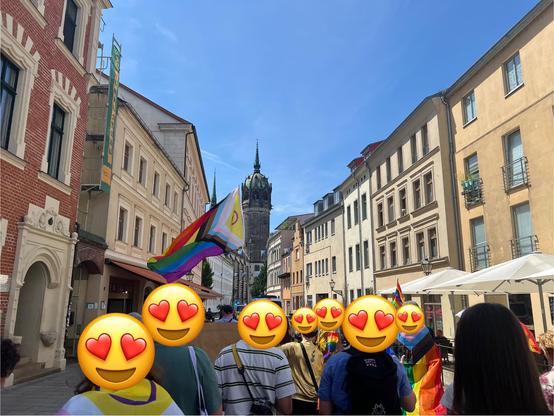 Demozug durch die Schlossstraße, im Hintergrund die Schlosskirche. Vorn wird eine Pride Flag getragen.