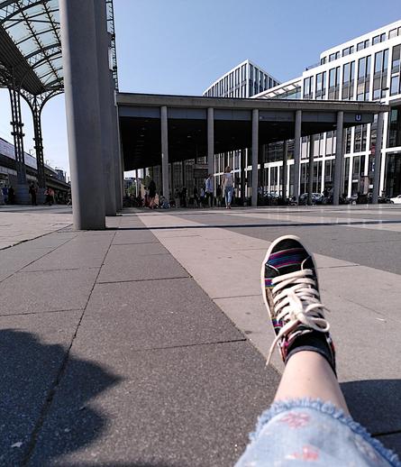 Im Vordergrund Fees Fuß, sie sitzt auf dem Boden des Breslauer Platzes in Köln.