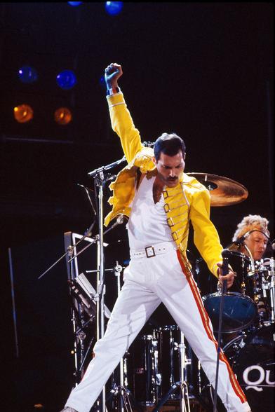 Classic photo of Freddie Mercury in his white jumpsuit and yellow jacket.
