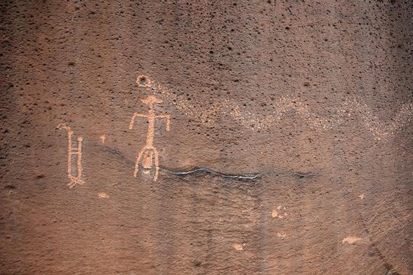 Simple pecked figures with two figures embracing next to a single figure with legs spread and a baby figure between her legs. A lightly pecked serpentine form comes in from the right side and ends about the mother figure.