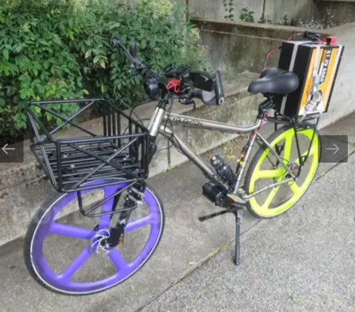a monstrosity of a bike, with purple and yellow aero rims, a titanium frame, a front cargo basket and a gigantic battery strapped to the rear. 