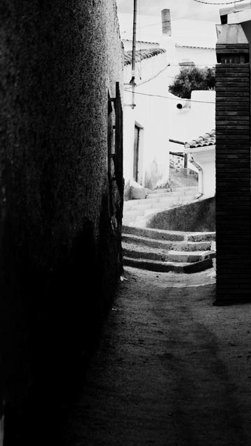 A narrow streets ends in some curved steps 
