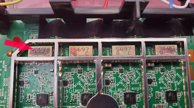 Photo of a Netgear ORBI RBR50 router PCB board. A red arrow points to a metal can near an antenna connection. The metal is discolored with brown splotches, as if it may have overheated.
