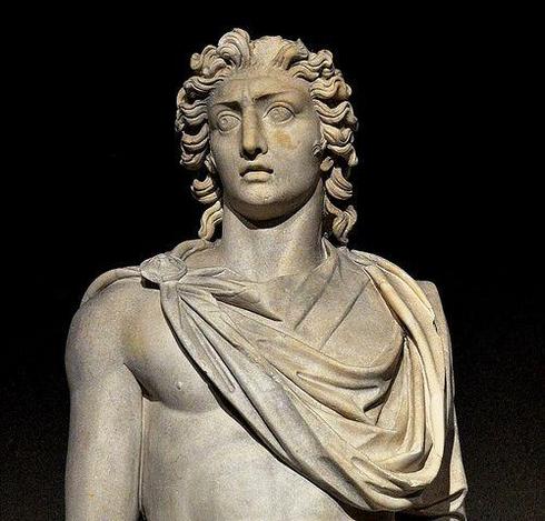 Colossal sculpture of the Sun God Helios from the late Roman Imperial period. It weighed 2.5 tons. A detail of the sculpture is shown in the photo, showing him from head to mid-torso. His head has short, curly hair and stern eyes. He wears a cloak pinned over his right shoulder, leaving one nipple bare. His arms are at his sides, possibly holding the reins of his chariot and a riding crop off screen.