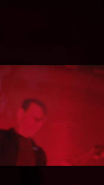 Das Video beginnt mit einer Person, die in einem roten Licht beleuchtet ist, was eine düstere und intensiv emotionale Atmosphäre schafft. Die Person trägt ein dunkles Oberteil und eine Halskette, und ihr Haar ist zu einem Knoten gebunden. Der Titel "DARKK TRAITOR" erscheint in großen, weißen und gelben Buchstaben über dem Bild, was auf eine mögliche Verbindung zu einem Musikvideo oder einer Musikproduktion hinweist. Die Person singt oder spricht in eine Mikrophone, was durch die Bewegung ihres …