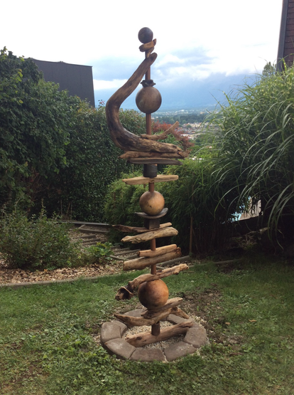 Braune und schwarze Keramikteile zu einer Säule aufgebaut. Dazwischen Holzstücke.